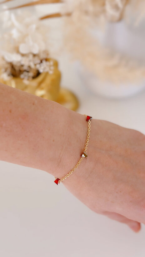 Rokas ķēdīte ar sarkaniem trijstūra stikliņiem.